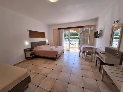 a hotel room with a bed and a table and chairs at Perla Beach in Agia Marina Nea Kydonias