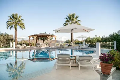 a swimming pool with chairs and a table and an umbrella at Villa Life in Agia Marina Nea Kydonias