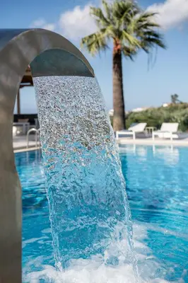 a fountain in the middle of a pool with a palm tree at Villa Life in Agia Marina Nea Kydonias