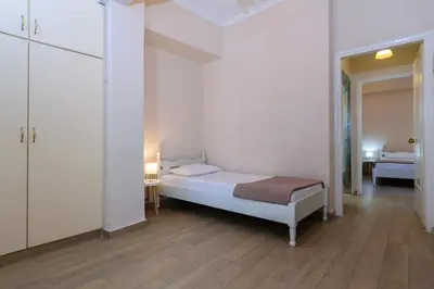 a white bedroom with a bed and a room with a table at Archontiki City Hotel in Chania Town