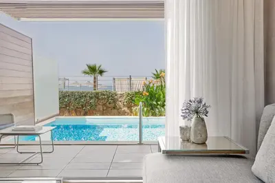 a living room with a view of a swimming pool at Minoa Palace Resort in Plataniás