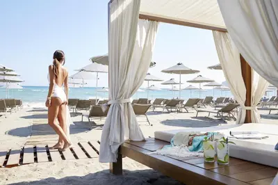 a woman in a bikini standing on a beach at Minoa Palace Resort in Plataniás
