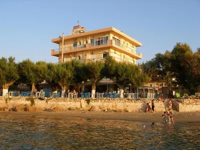 a building on the beach with people in the water at Melani Apartments in Chania Town