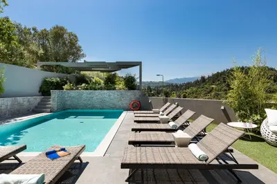 a row of chaise lounge chairs next to a swimming pool at Elea Villas - Aspro & Blanche in Almirida