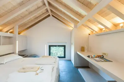 a bedroom with a large white bed and wooden ceilings at Elea Villas - Aspro & Blanche in Almirida