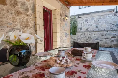 a table with plates and cups and a vase with flowers at PRIVATE Sapphiros Villa in Kissamos