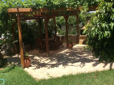 a wooden pergola with a table in a garden at Maria's Studios in Frangokastello