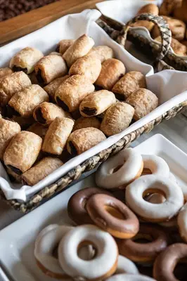 two trays of donuts and other pastries on a table at Cretan Dream Resort & Spa in Stalos