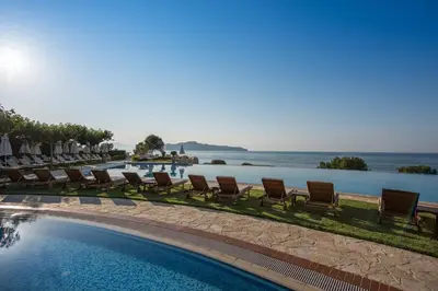 a pool with chairs and umbrellas next to the water at Cretan Dream Resort & Spa in Stalos