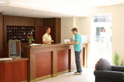 a man and a woman standing at a counter at Margarita Beach Hotel in Agia Marina Nea Kydonias