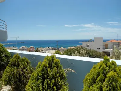 a view of the ocean from a balcony with trees at Petrakis sunset in Palaiochóra