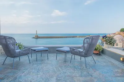 three chairs and a table on a balcony overlooking the ocean at Residenza Vranas Boutique Hotel in Chania Town