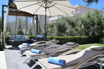 a row of lounge chairs with an umbrella at Sunlight Breeze Villa in Chania Town
