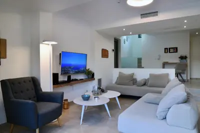 a living room with a couch and a tv on a wall at Sunlight Breeze Villa in Chania Town