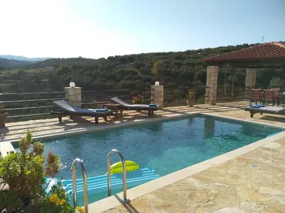 a swimming pool with two chairs and a gazebo at Little House on the Prairie - Chania in Katokhórion