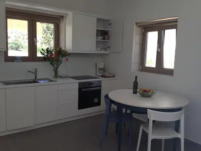 a white kitchen with a table and a sink at Anny's Homes in Kountoura Selino
