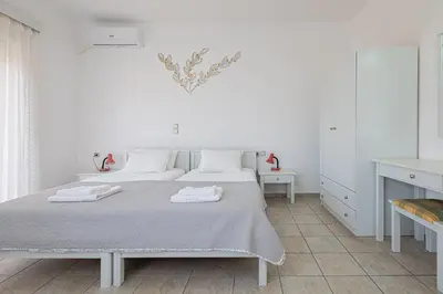 two beds in a white room with a heart on the wall at Marias Studios & Apartments in Platanias in Plataniás