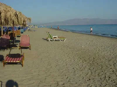 a beach with chairs and people on the water at Marias Studios & Apartments in Platanias in Plataniás