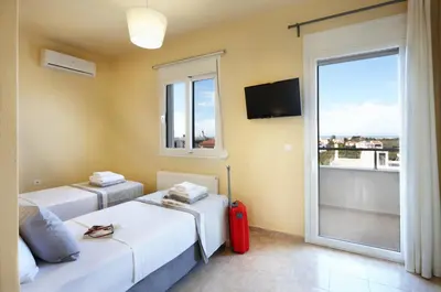 two beds in a room with a window and a red suitcase at Dream Villa in Kambánion
