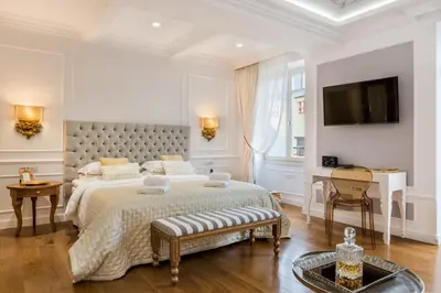 a white bedroom with a large bed and a tv at Casa Kallergi in Chania Town
