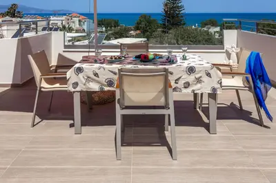 a table and chairs on a balcony with the ocean at Angels Suites in Plataniás
