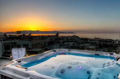 a hot tub on a roof with a sunset in the background at Angels Suites in Plataniás