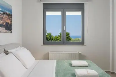 a white bedroom with a bed and a window at Elysium Seaview Oasis in Kato Galatas