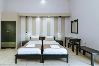 a bedroom with two beds and a desk and a mirror at Gelina Apartments in Plataniás