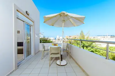 a balcony with a table and an umbrella at Gelina Apartments in Plataniás