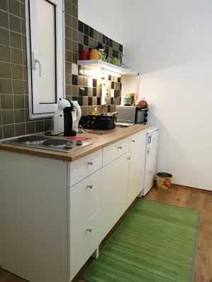 a kitchen with white cabinets and a green rug at City Square Apartment in Chania Town