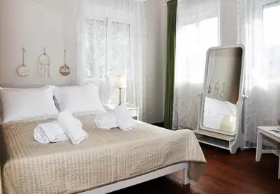 a bedroom with a bed with white pillows and a mirror at Villa Lakki Heated round pool Jacuzzi in Lákkoi