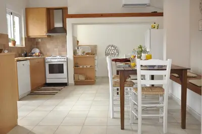 a kitchen with a table and white appliances at Villa Lakki Heated round pool Jacuzzi in Lákkoi