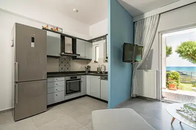 a kitchen with a refrigerator and a table and a window at Big Blue Villa in Kisamos, 10 meters from Sea in Kissamos