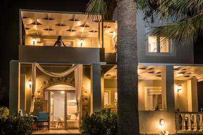 a man sitting on the balcony of a building at night at Big Blue Villa in Kisamos, 10 meters from Sea in Kissamos