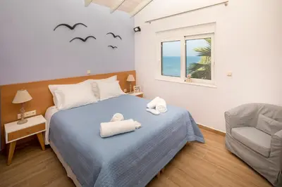 a bedroom with a bed and a chair and a window at Big Blue Villa in Kisamos, 10 meters from Sea in Kissamos