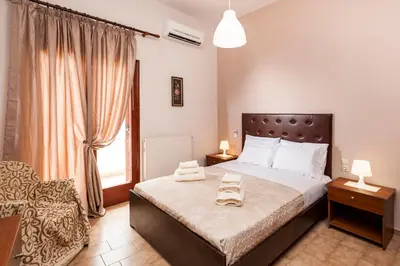 a bedroom with a bed and a chair and a window at Falassarna House in Plátanos