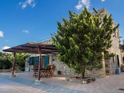 a tree in front of a house with a table and chairs at Villa Kimothoe with Private Pool, only 20 min to Elafonissi Beach in AmigdhalokeFálion