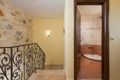 a bathroom with a walk in shower next to a stone wall at Adam Villas in Falasarna