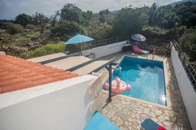 a house with a swimming pool and an umbrella at Villa Afou in Afráta