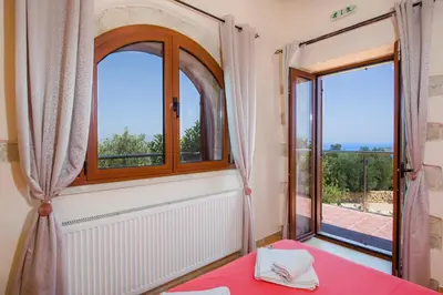 a room with two windows and a table with a red table cloth at Villa Kourouni in Stalos