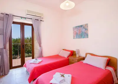 two red beds in a room with a window at Villa Kourouni in Stalos