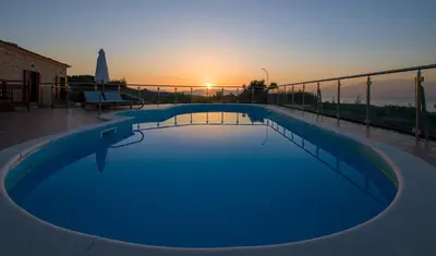 a swimming pool with the sunset in the background at Villa Kourouni in Stalos