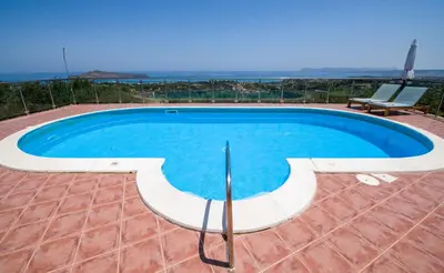 a swimming pool on a patio with a chair next to it at Villa Kourouni in Stalos
