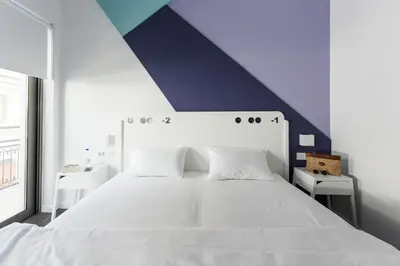 a bedroom with a white bed with a purple wall at Cocoon City Hostel in Chania Town