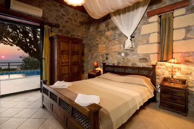 a bedroom with a bed and a balcony with a view at Sea-Sunset Views Villa Lefkothea with Private Pool near Elafonissi in AmigdhalokeFálion