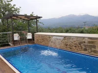 a pool with a waterfall and a table and chairs at Stone Mansion in Káïna