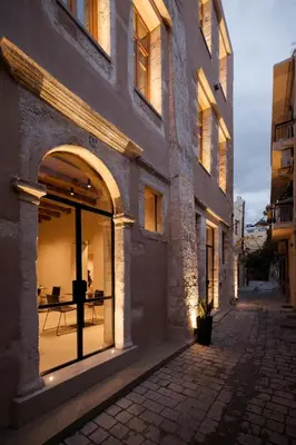 a building with large windows with a table in the distance at Monastery Estate Venetian Harbor in Chania Town