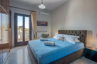a bedroom with a bed with blue sheets and a window at Nikola's Villa Stalos Chania in Stalos