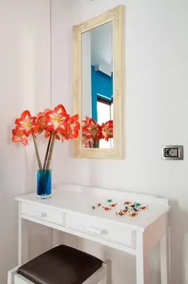a white dressing table with a mirror and a vase with flowers at Kallitsakis Beach in Plataniás