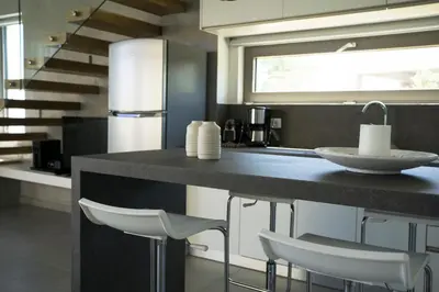 a kitchen with a counter with stools and a sink at Iskios Villas in Agia Marina Nea Kydonias